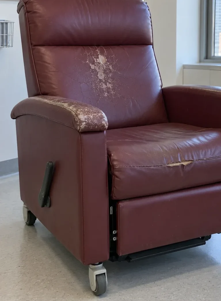 A burgundy infusion recliner with cracked arms
