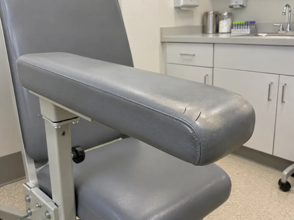 A worn gray vinyl blood draw arm rest
