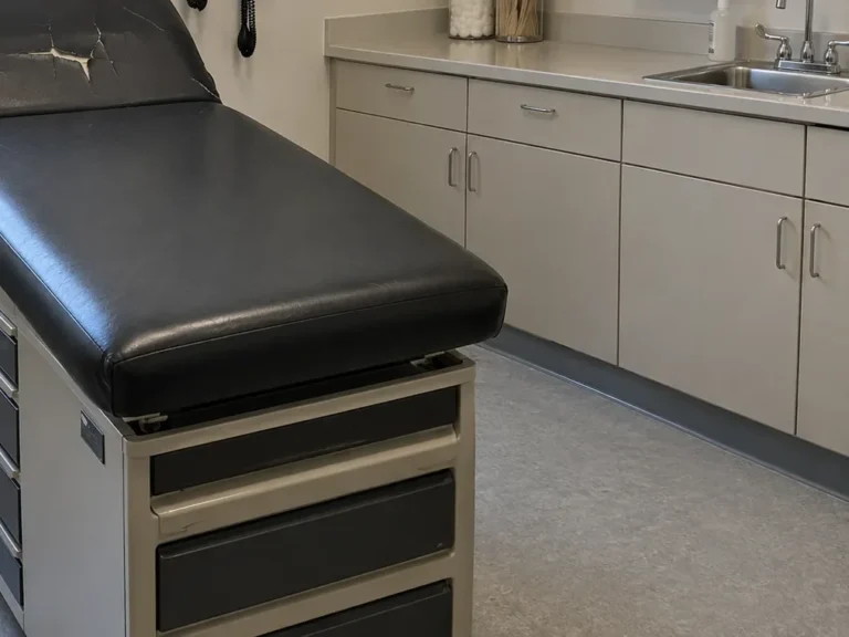 An exam table with cracked black vinyl