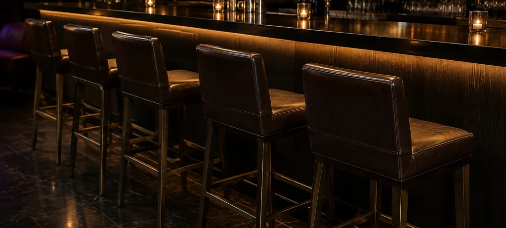 Leather bar stools lined up along a dark club bar