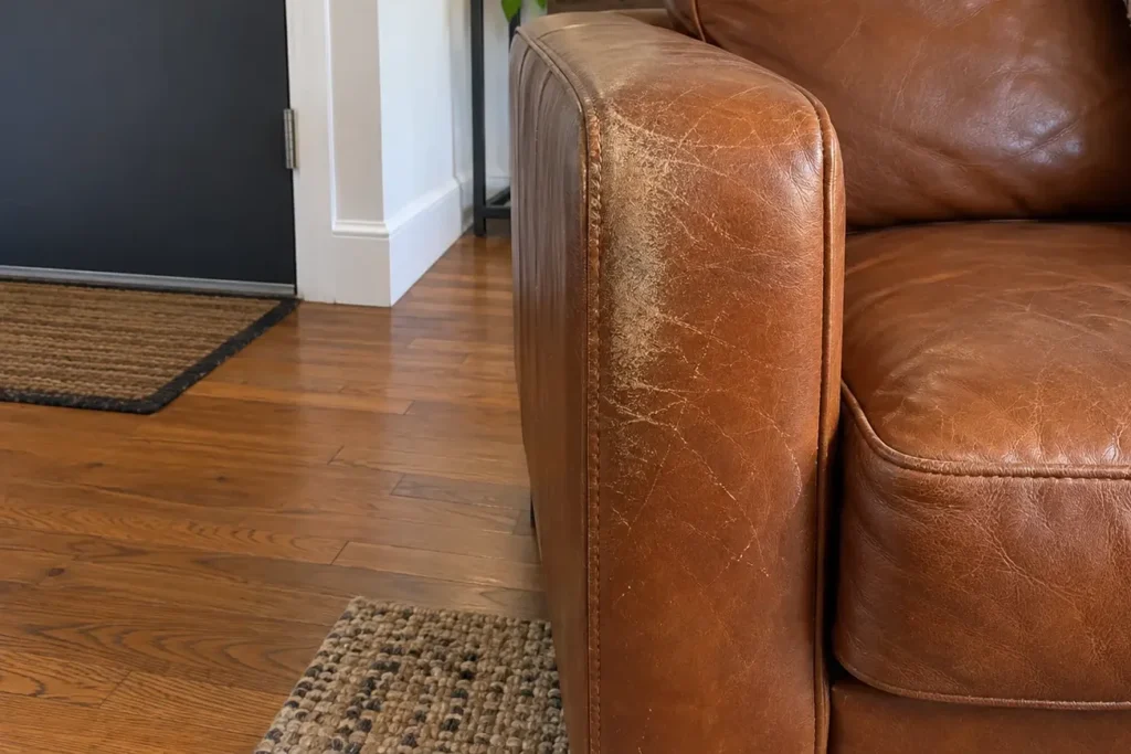 Luggage scuffs on the arm of a leather sofa in a furnished rental