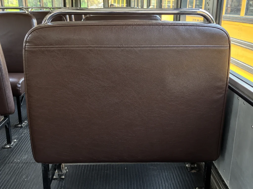 The thick padded back of a school bus bench