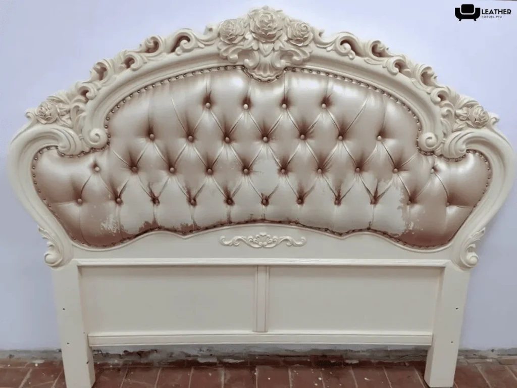 A carved tufted headboard with worn pearl upholstery
